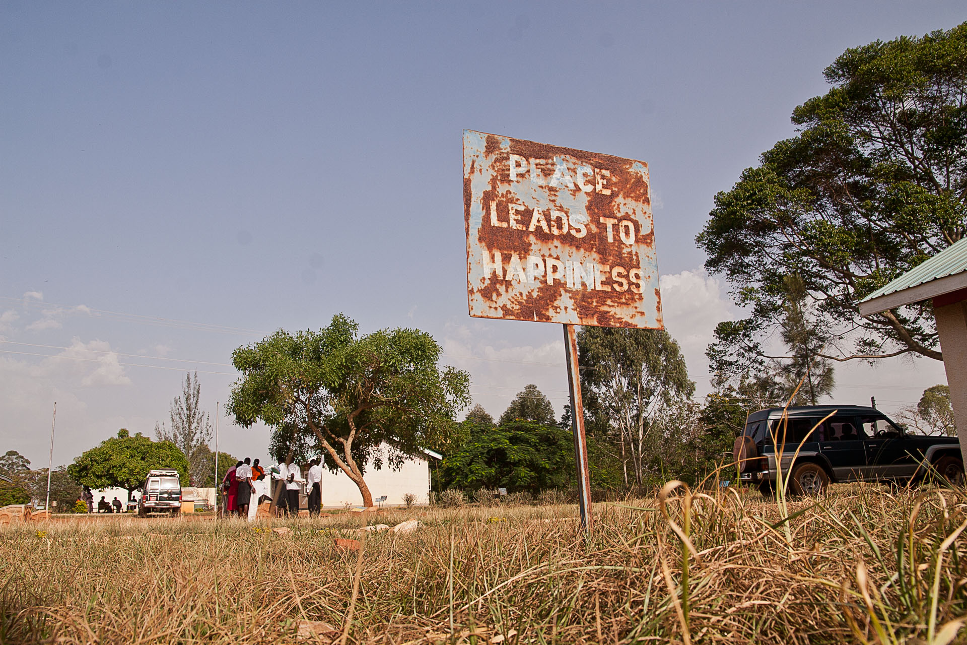 Rusty roadside sign that reads 'peace will make us happy'