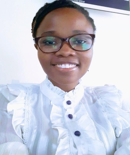 Headshot of a smiling African lady wearing glasses and a white shirt