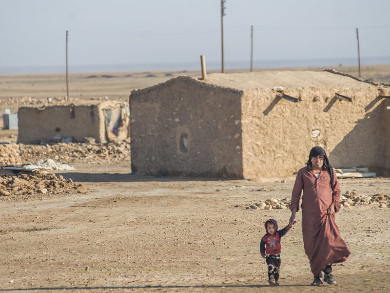 Man and small child walking through a blasted, desert landscape