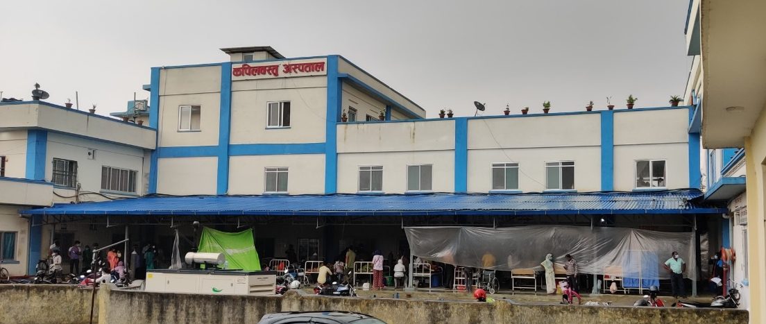 Outside view of a hospital - people in masks are standing outside