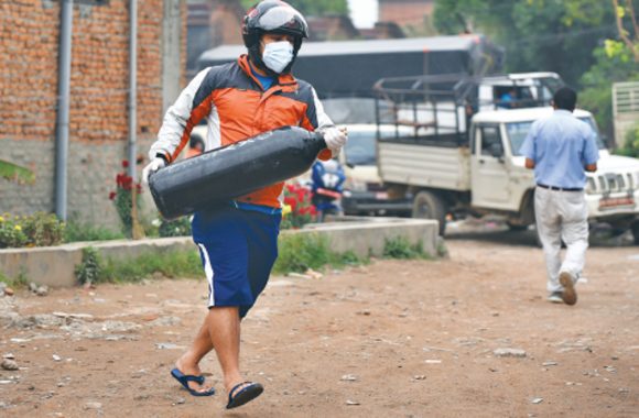 A man with a face mask carrying an ixygen cylinder across a road