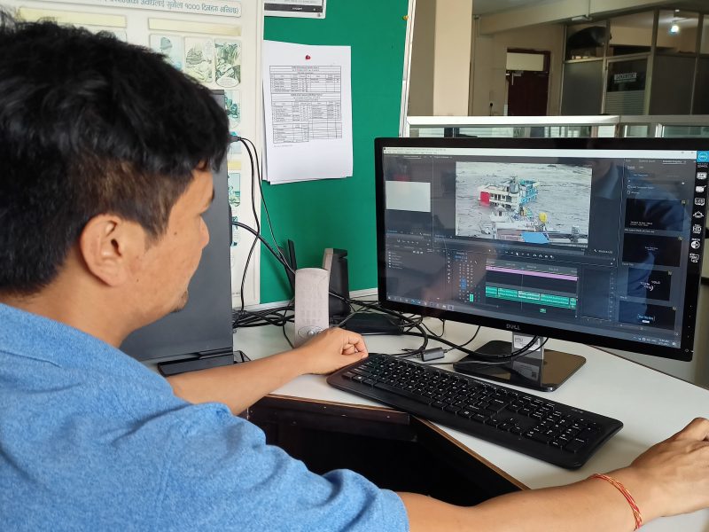 Dark-haired man in blue tshirt working at a computer