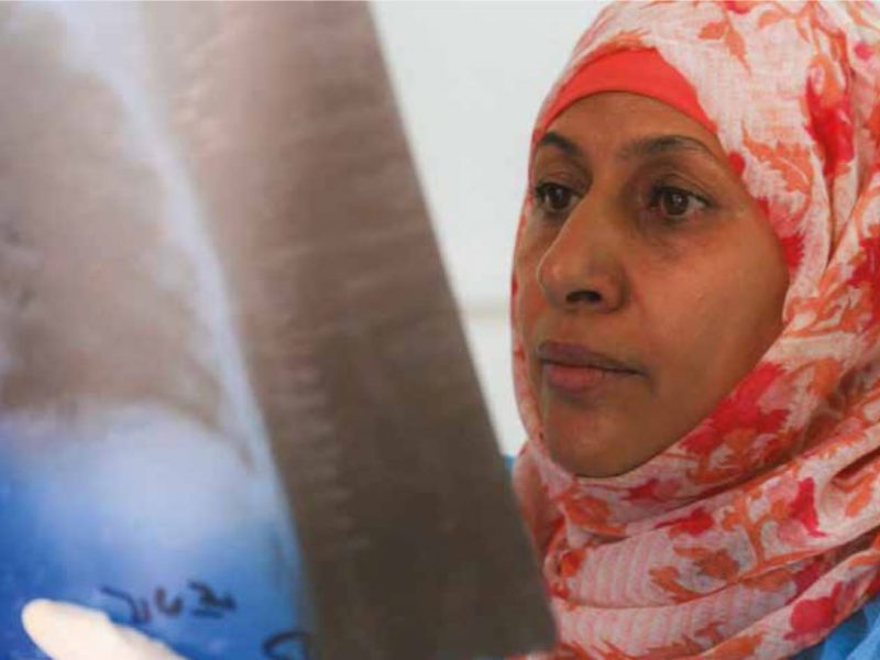 Headshot of a woman wearing a headscarf looking intently at a chest xray