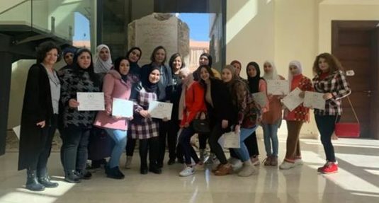 A group of standing, smiling young women holding certificates - some of the women are wearing headscarves