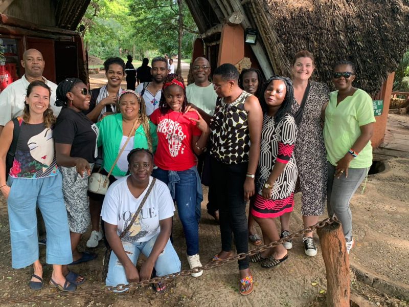 A group of smiling men and women outside a wooded area