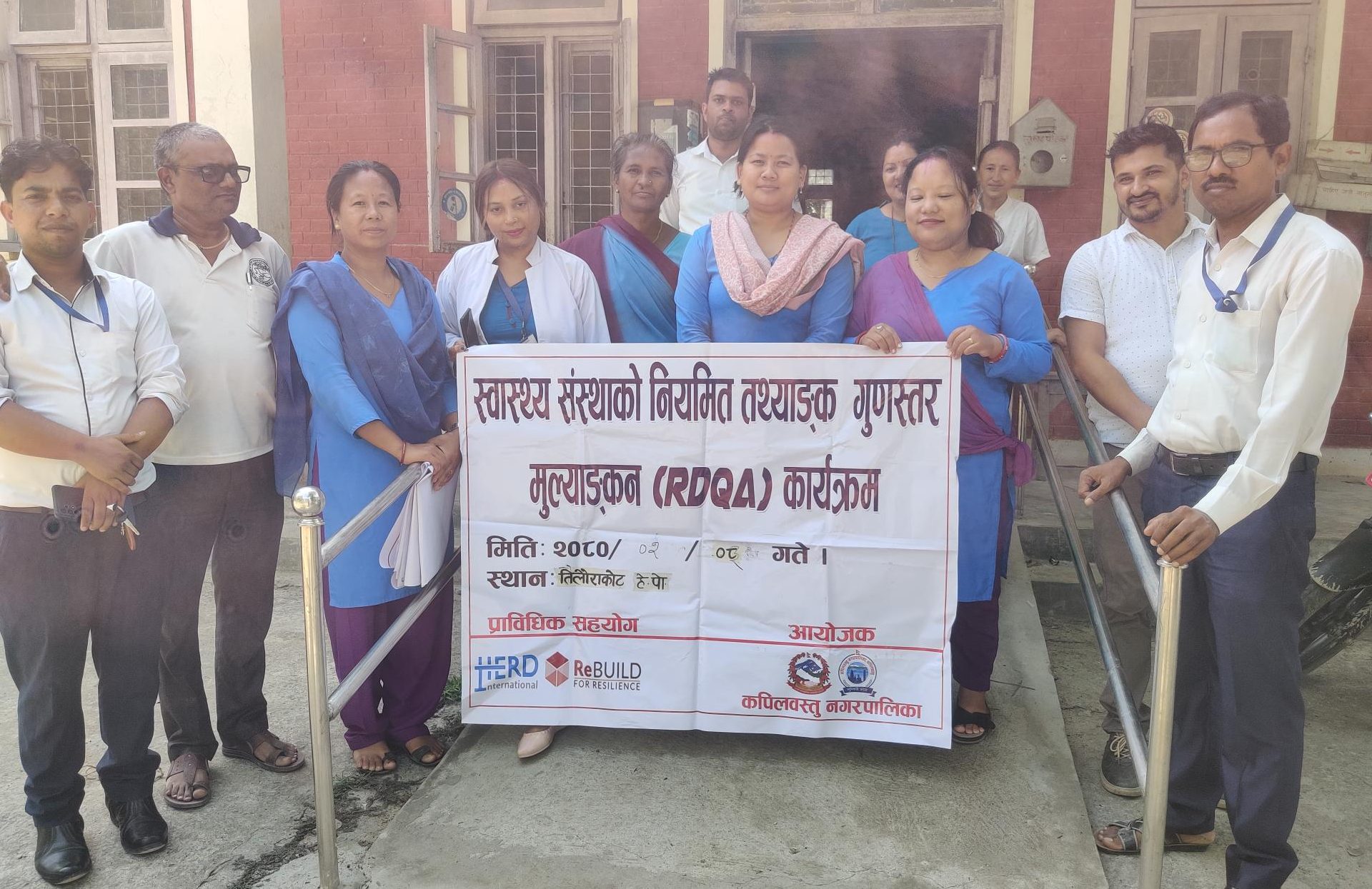 A group of health workers holding a sign outside a health facility