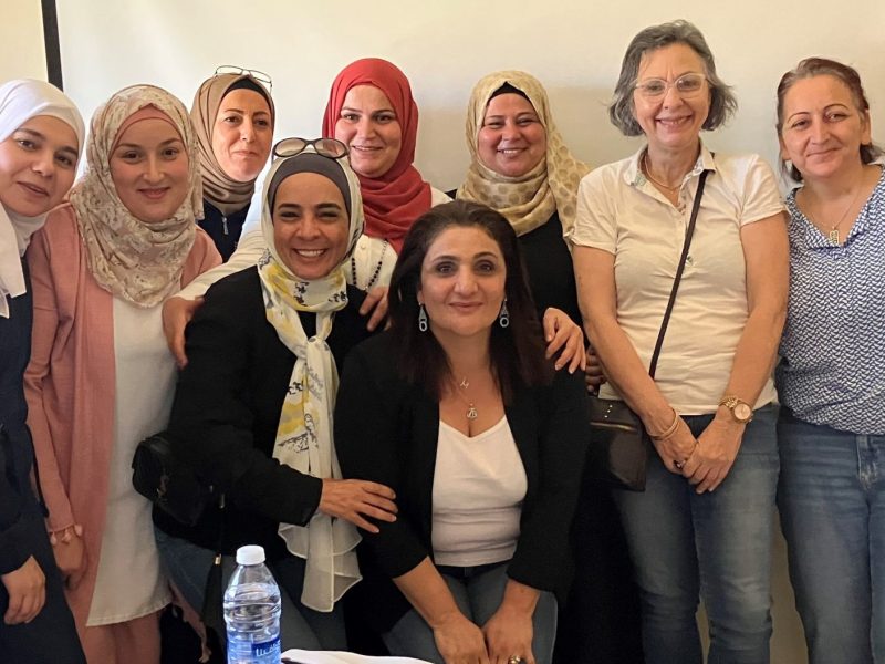 A group of smiling women, most of whom are wearing headscarves
