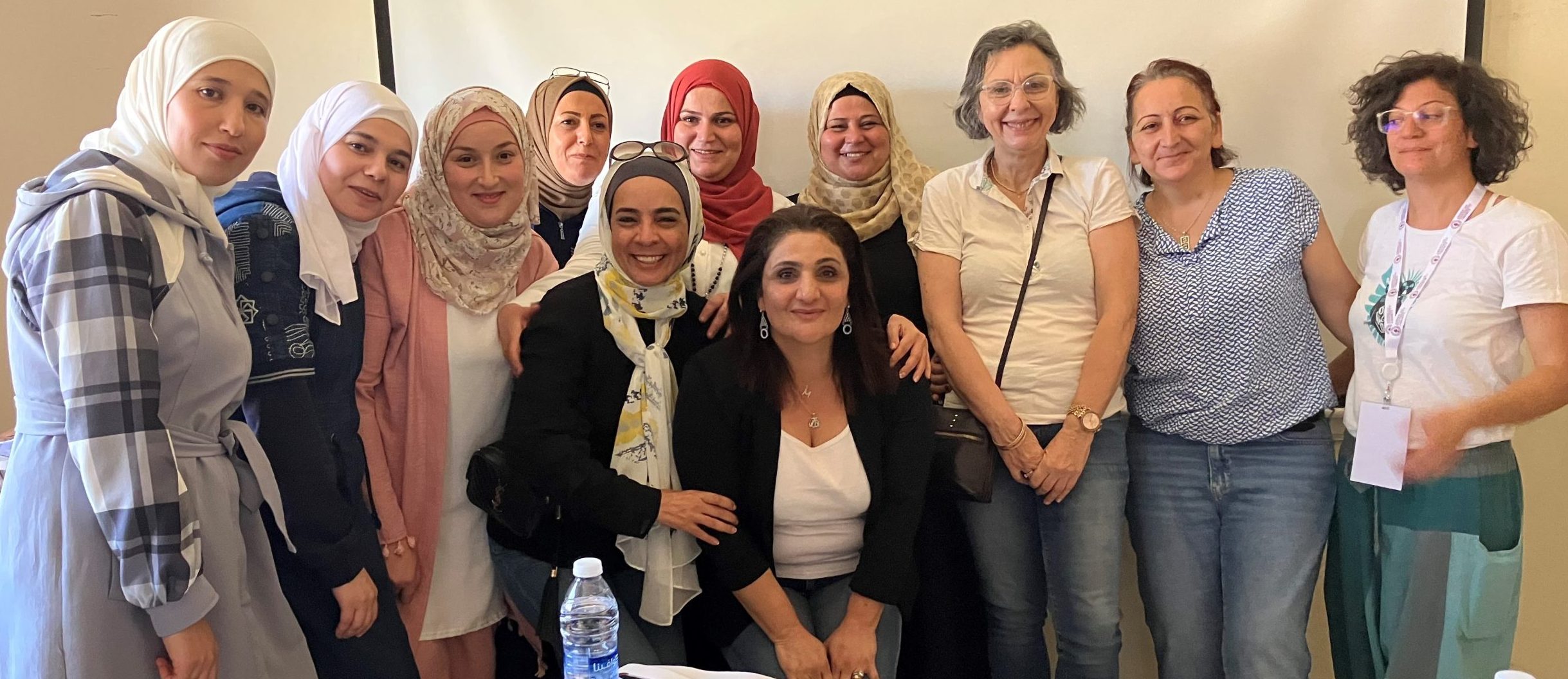 A group of smiling women, most of whom are wearing headscarves