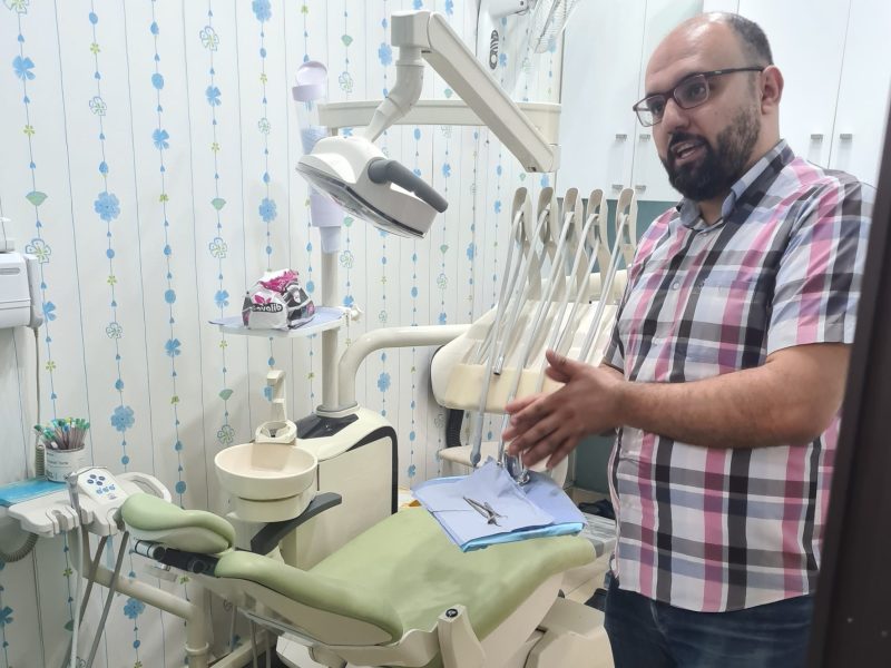 A Syrian man stands talking in a medical examination room