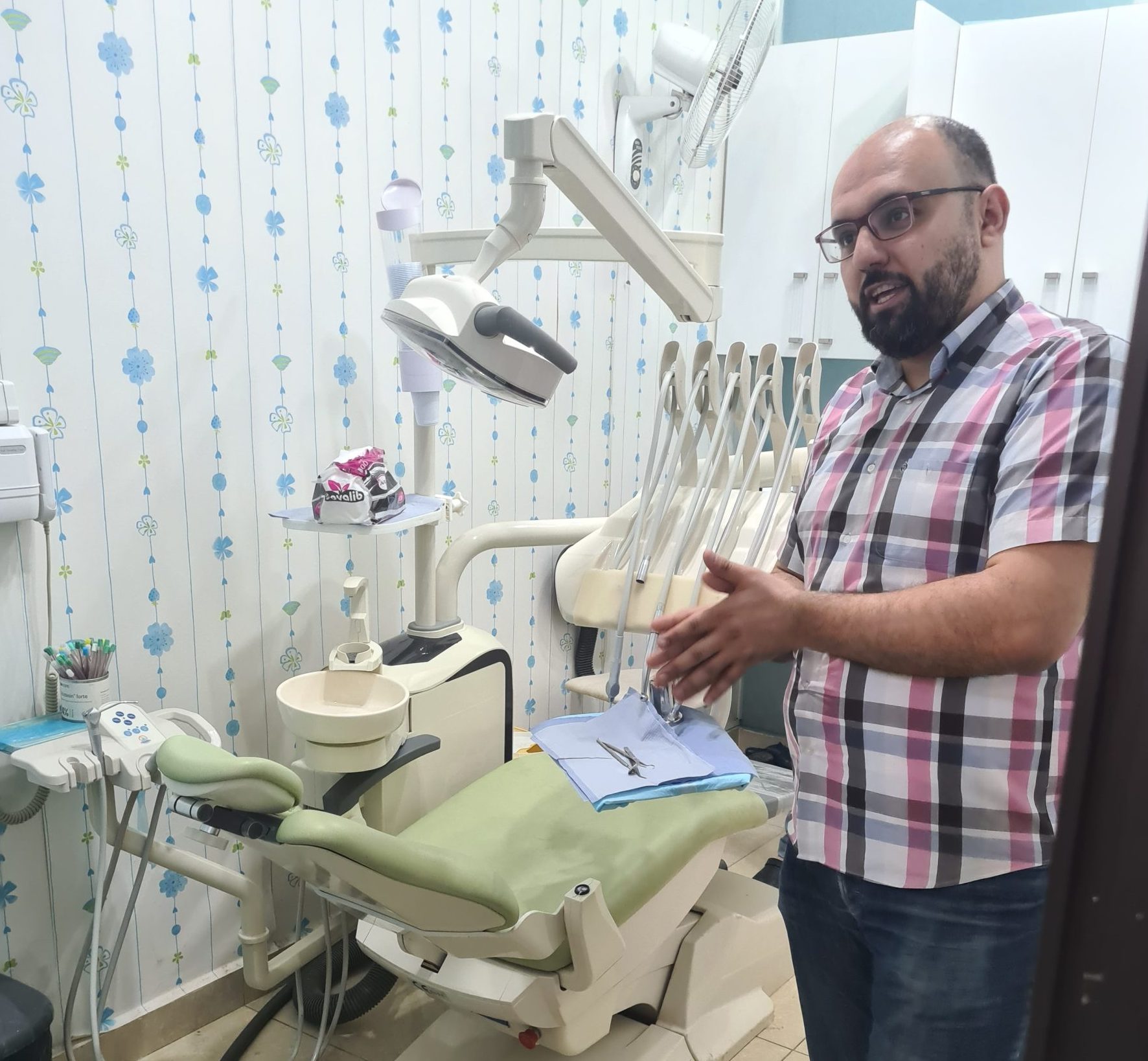 A Syrian man stands talking in a medical examination room