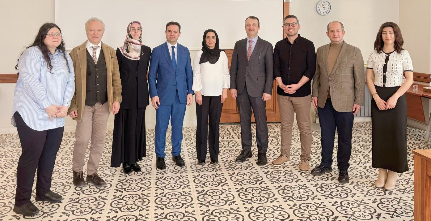 A row of nine smiling men and women in a room with a tiled floor