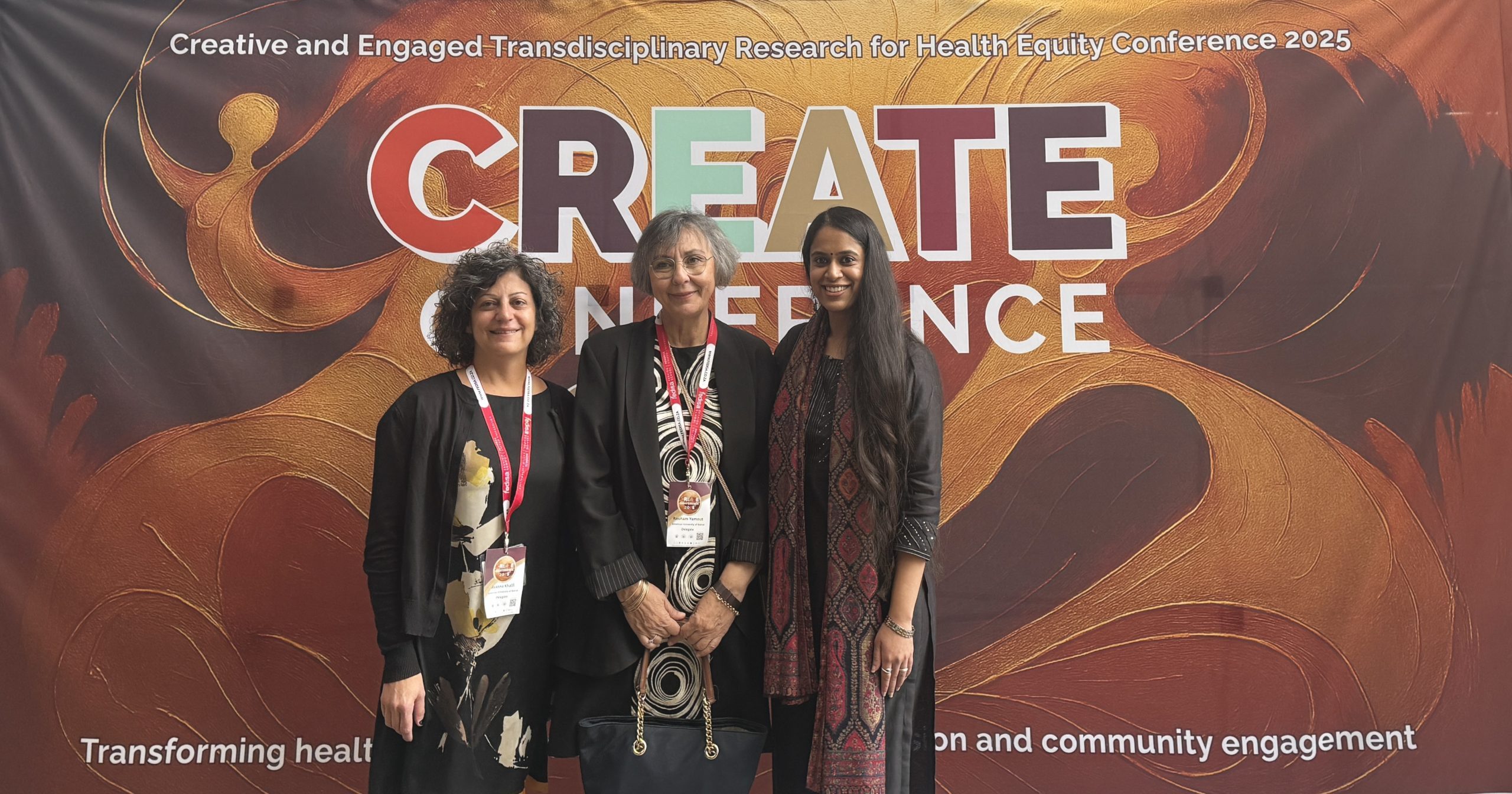 Three women stand smiling in front of a large banner with the words 'Create conference' on it