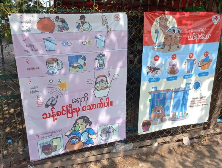 Two large posters attached to outdoor railings. Both feature diagrams and simple text.