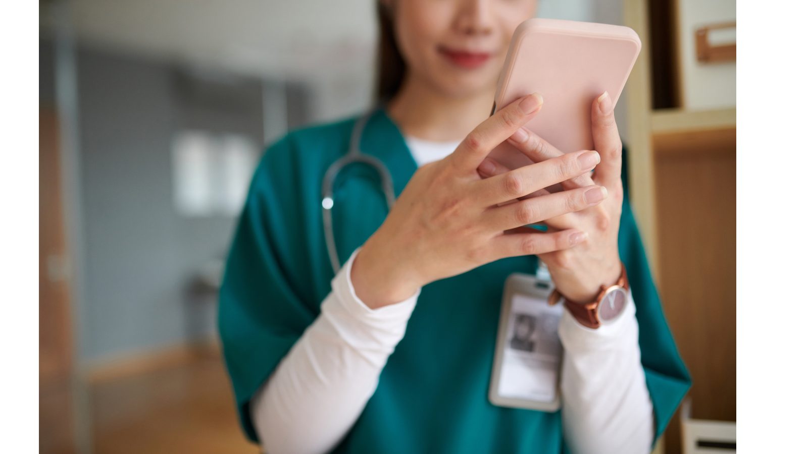 Photograph of a female medic in green uniform looking at their pink phone