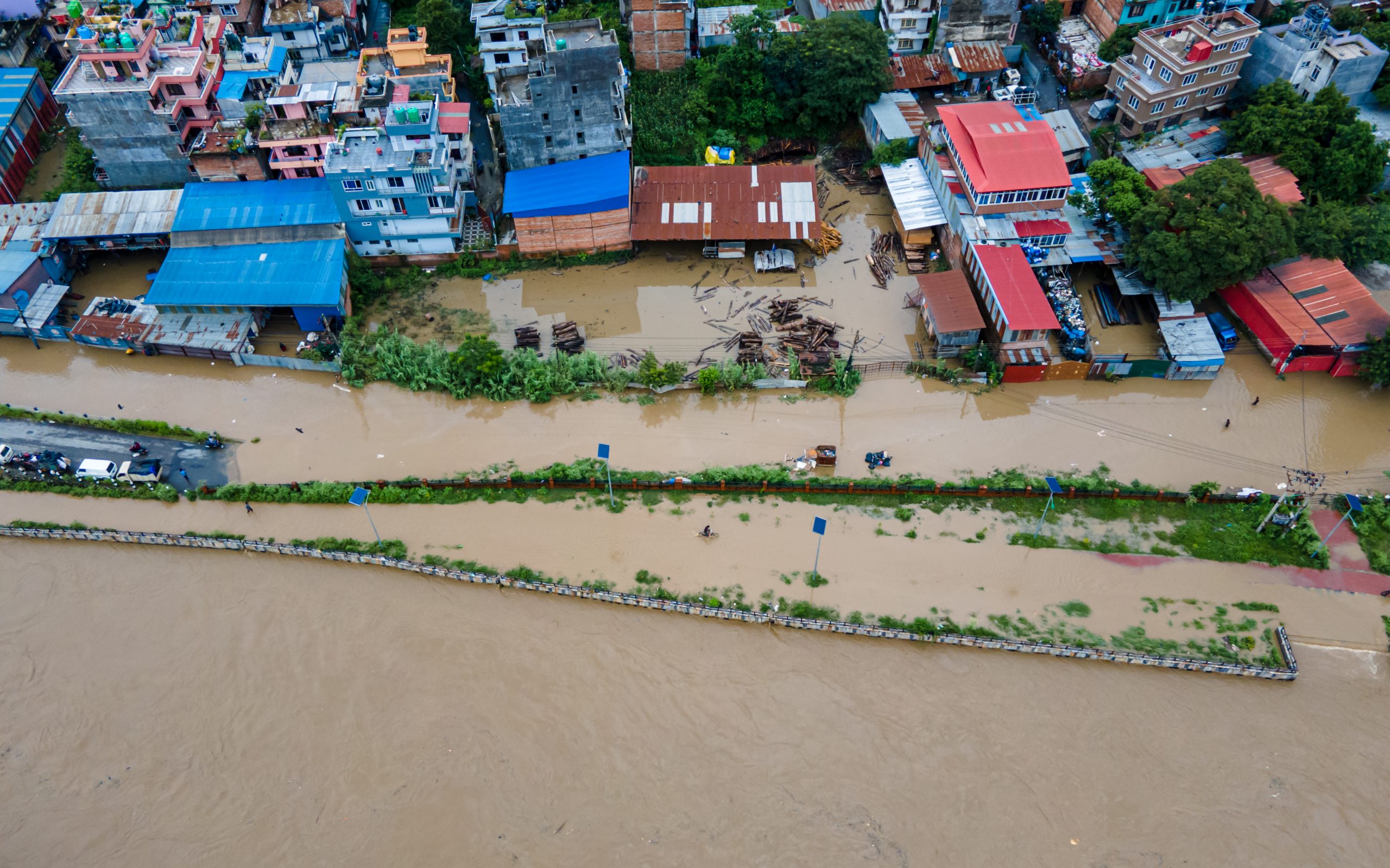 A river has flooded, engulfing buildings with red and blue roofs